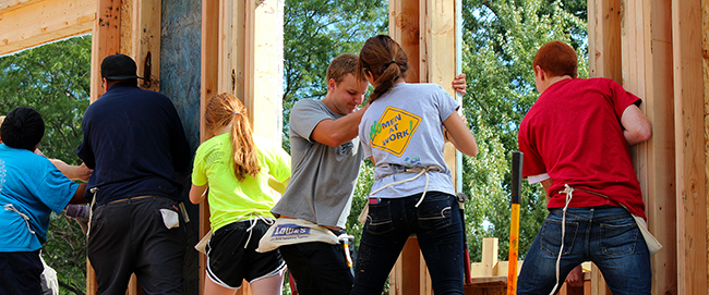 High school students help frame a wall