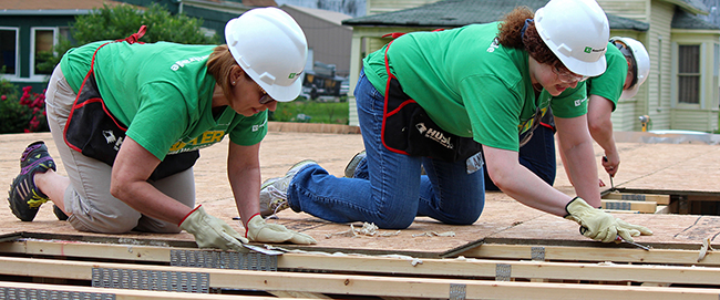 Female construction volunteers work on decking