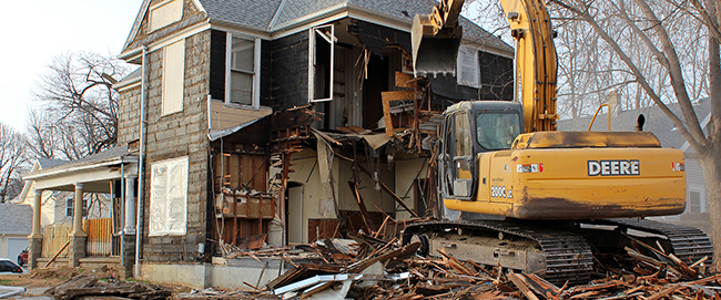 Excavator demolishes a house