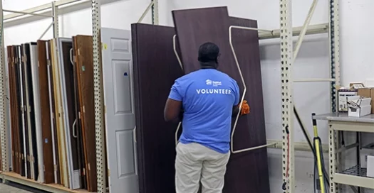 a volunteer at the Habitat Omaha ReStore faces backward, helping organize the display of doors to sell, with funds going to help Habitat Omaha build more affordable houses.