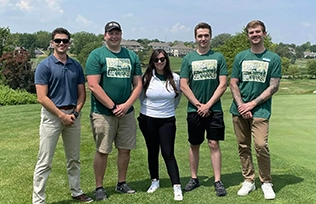 A group of young professionals pose on a golf course at a Habitat Omaha event.